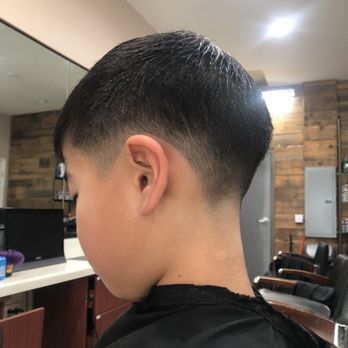 Boy with a faded haircut in a barbershop; dark hair, skin tone.