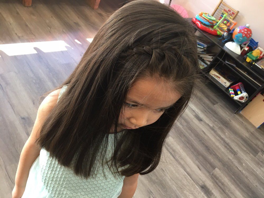 Smiling redhead child getting hair styled at salon.