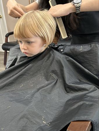 Boy with tousled brown hair and green eyes, wearing a grey shirt.