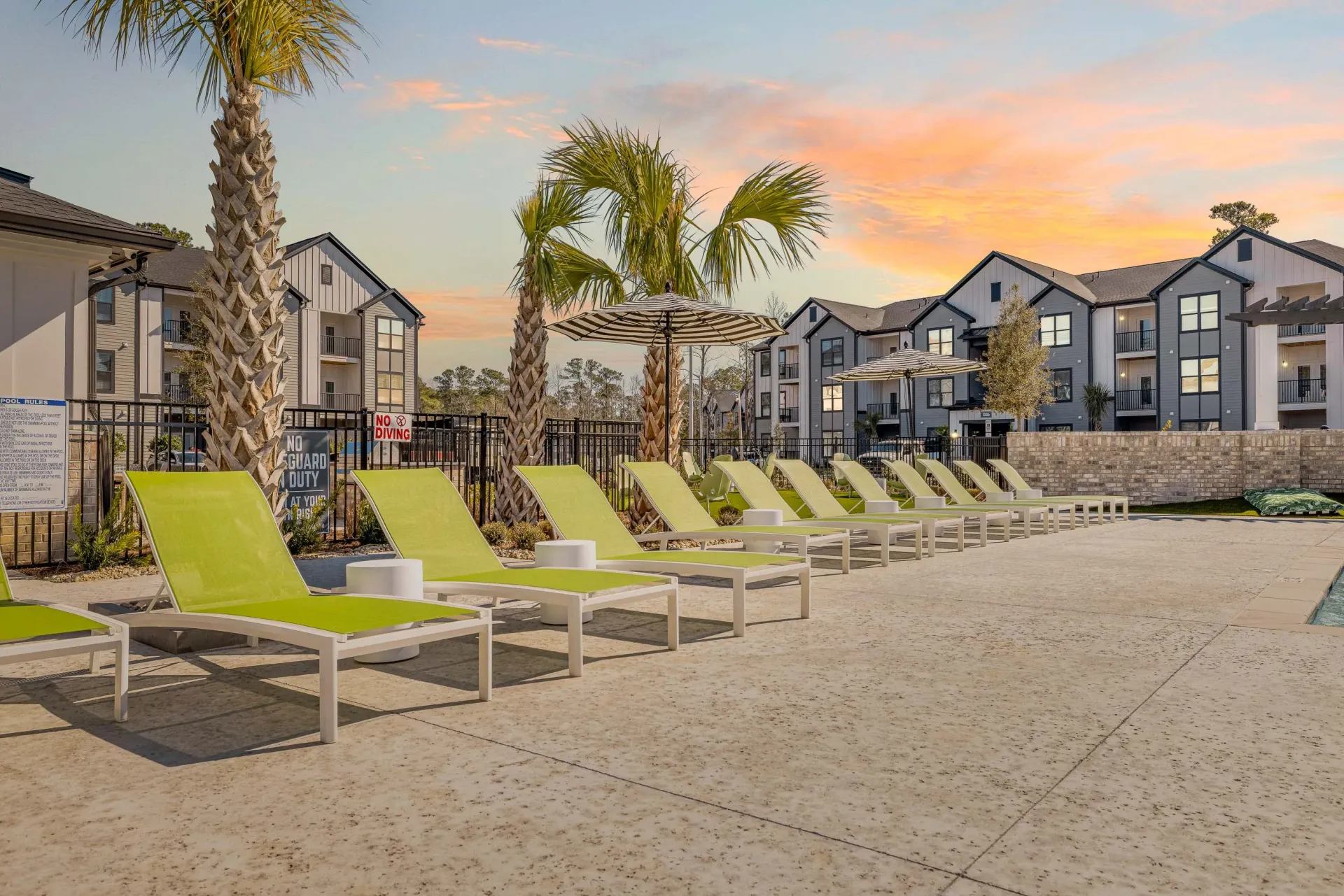 A row of green lounge chairs are lined up in front of a building.