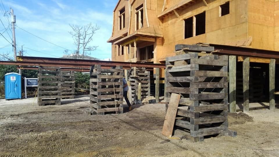 A row of wooden pallets are sitting in front of a building under construction.
