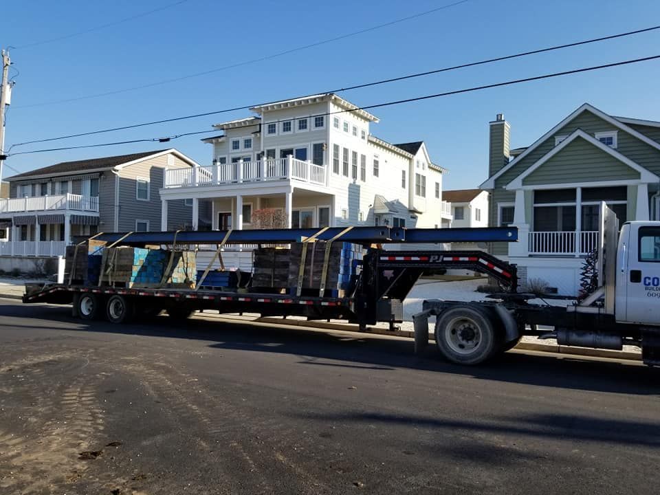 A white truck with a flatbed is parked in front of a house