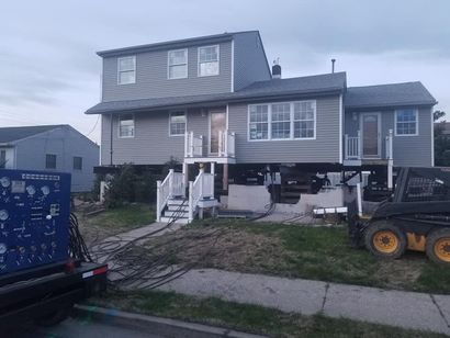 A house is being lifted by a bulldozer.
