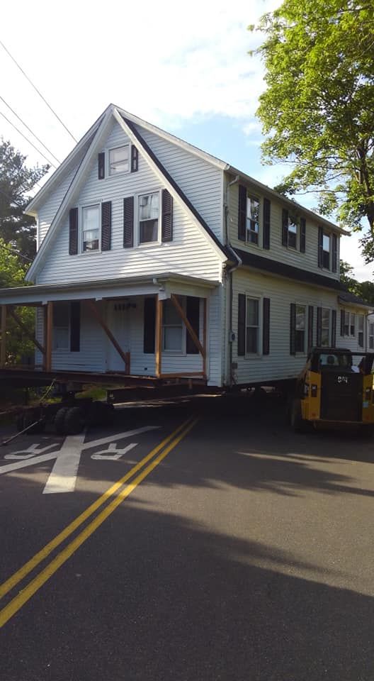 A large white house is being moved down a street