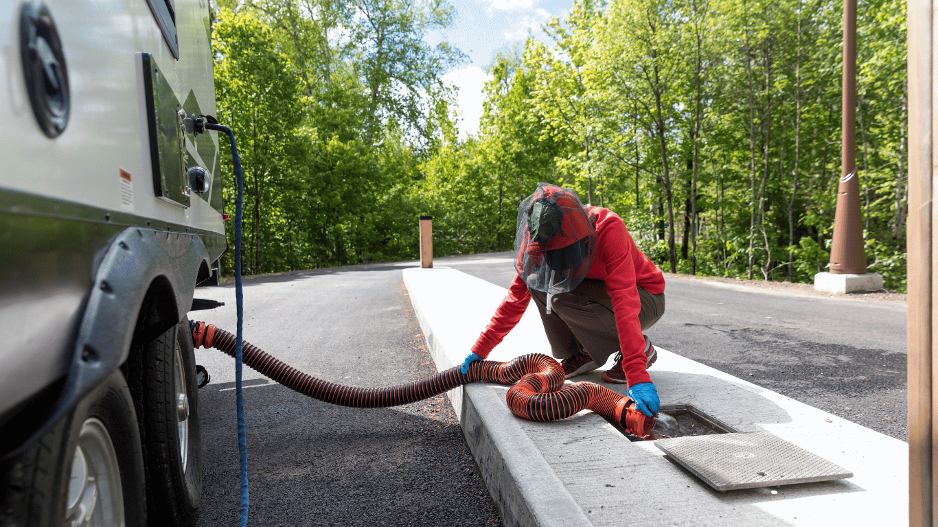 A man is pumping water into a septic tank with a hose.