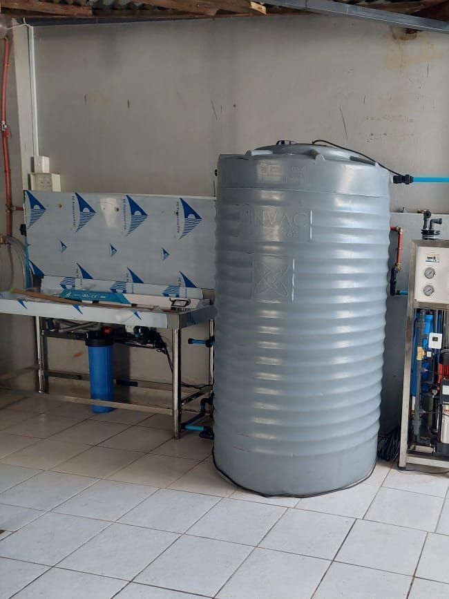 A large gray water tank is sitting in a room next to a sink.