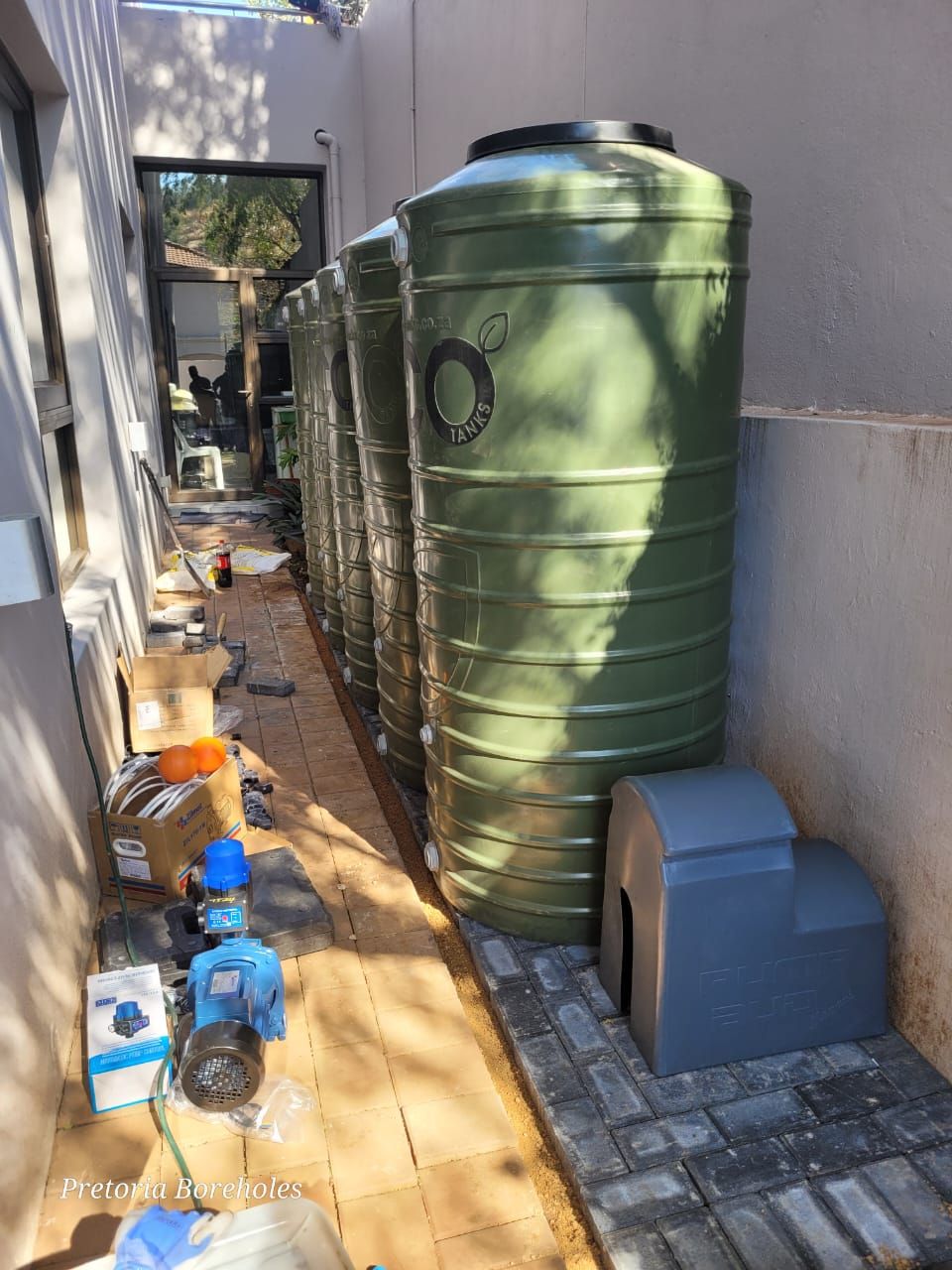 A row of green water tanks sitting next to each other on a sidewalk.