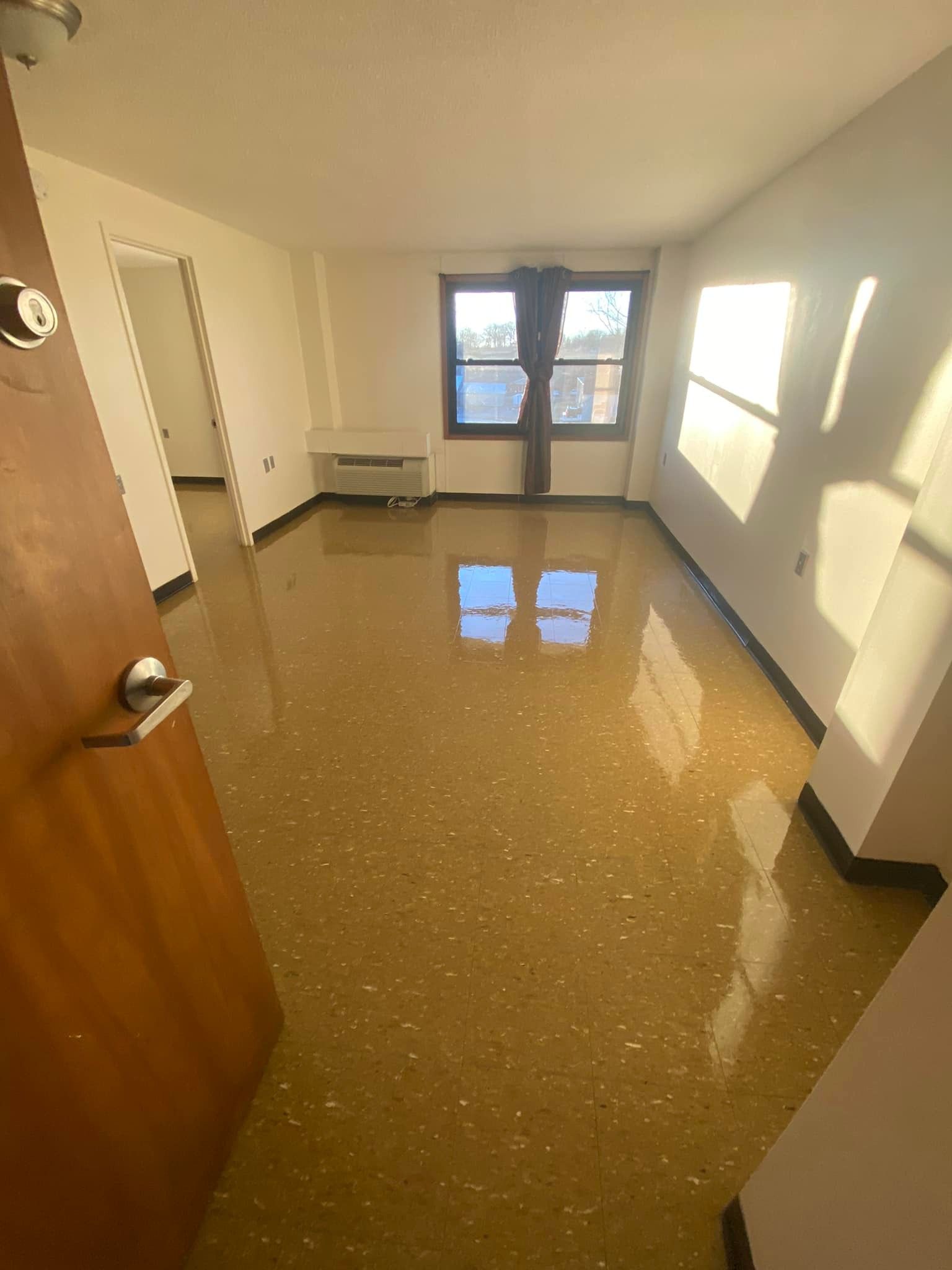 A living room with a shiny floor and a window.