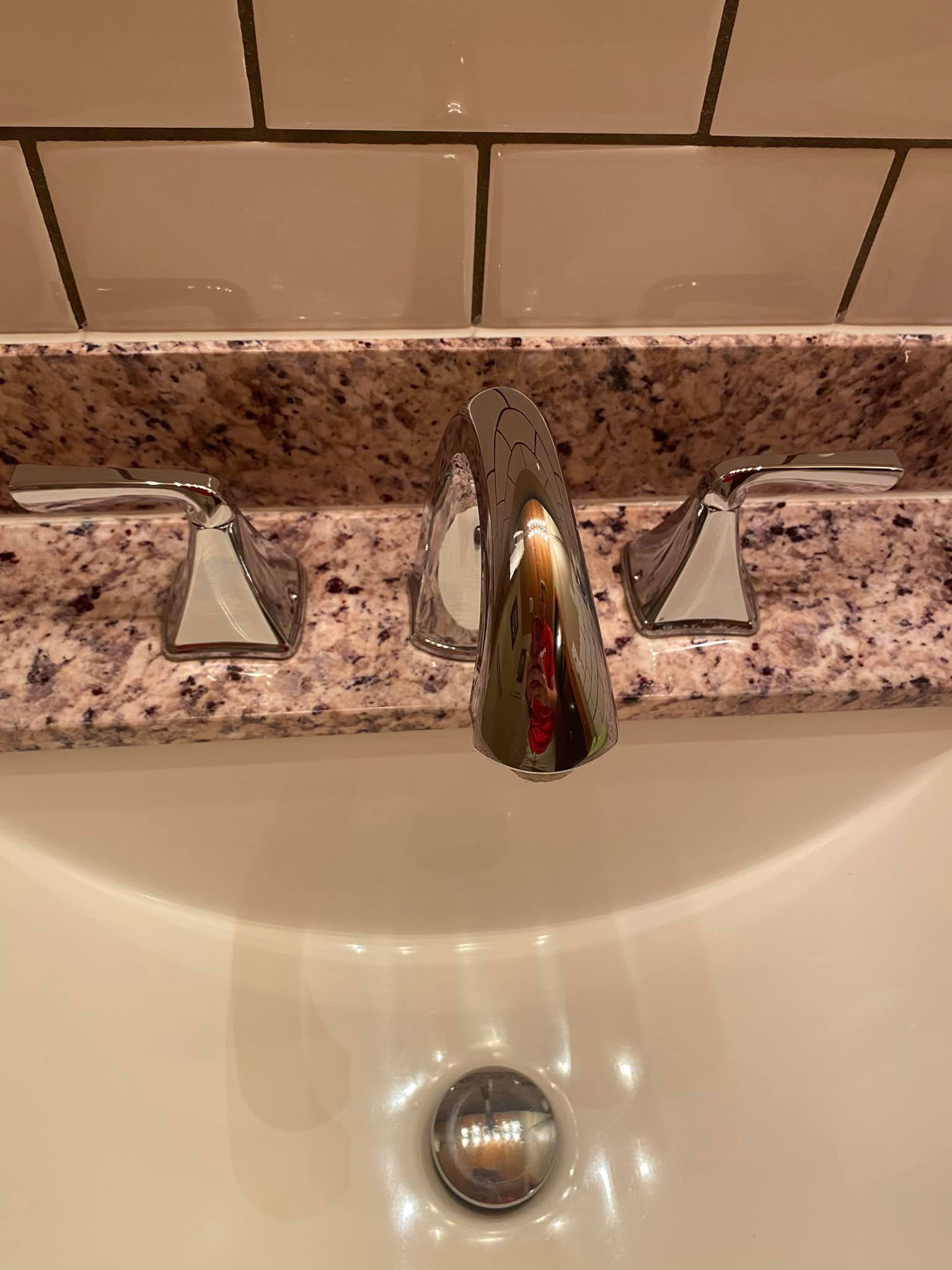 A bathroom sink with a faucet and a granite counter top.