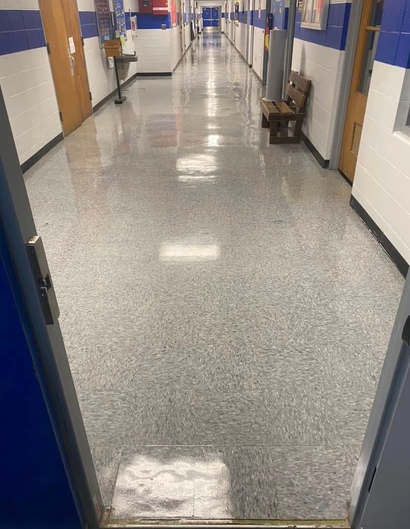 A long hallway with a bench in the middle of it.