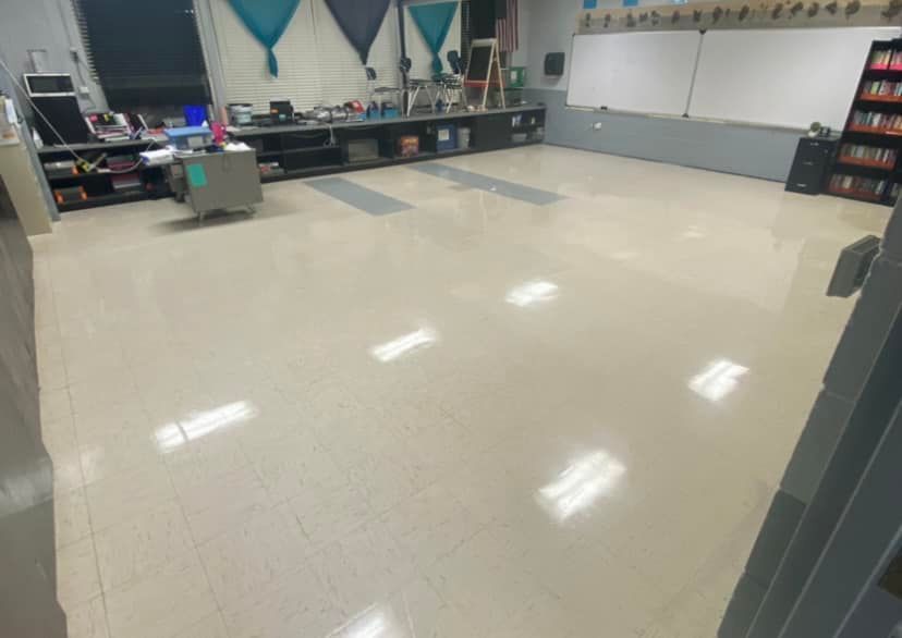 A large empty classroom with a whiteboard and a desk.