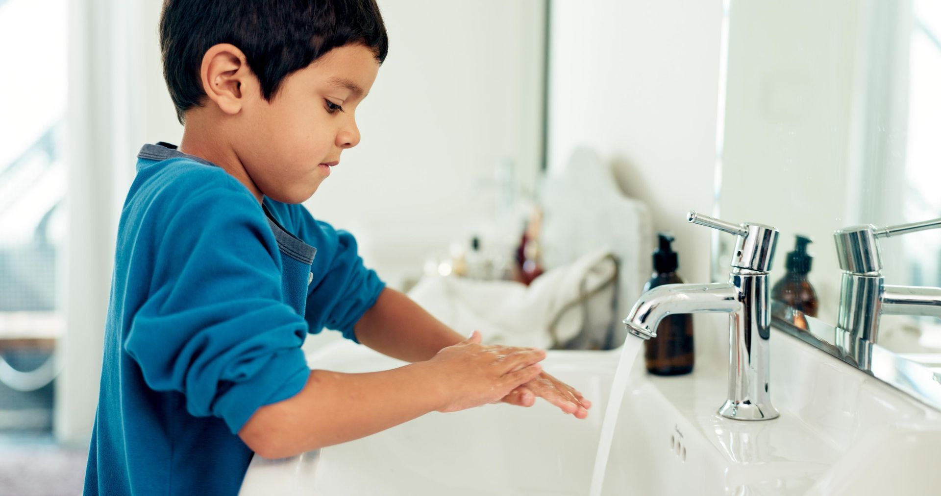 A young boy is washing his hands in a bathroom sink.