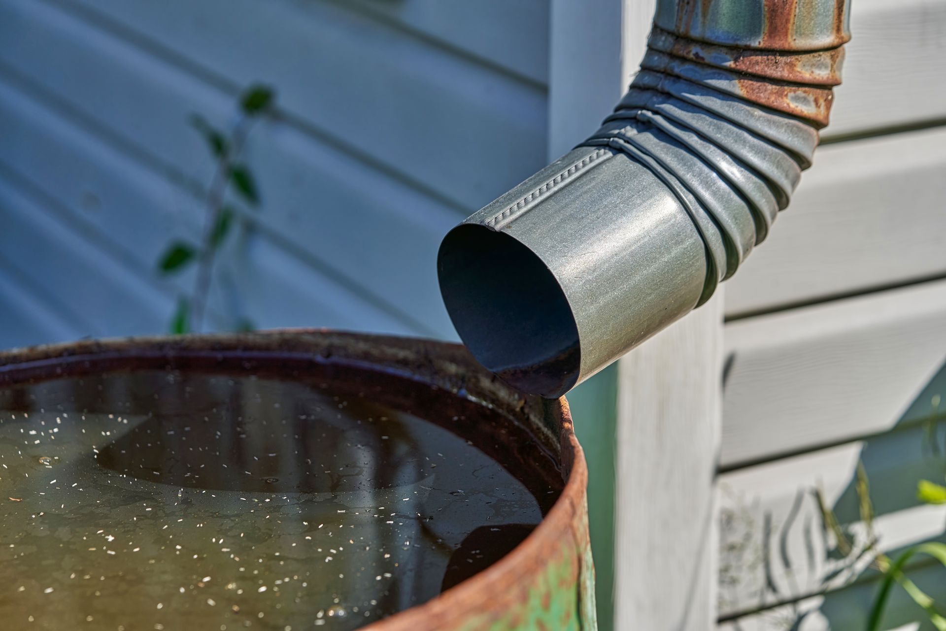 A close up of a rain barrel with water coming out of it.