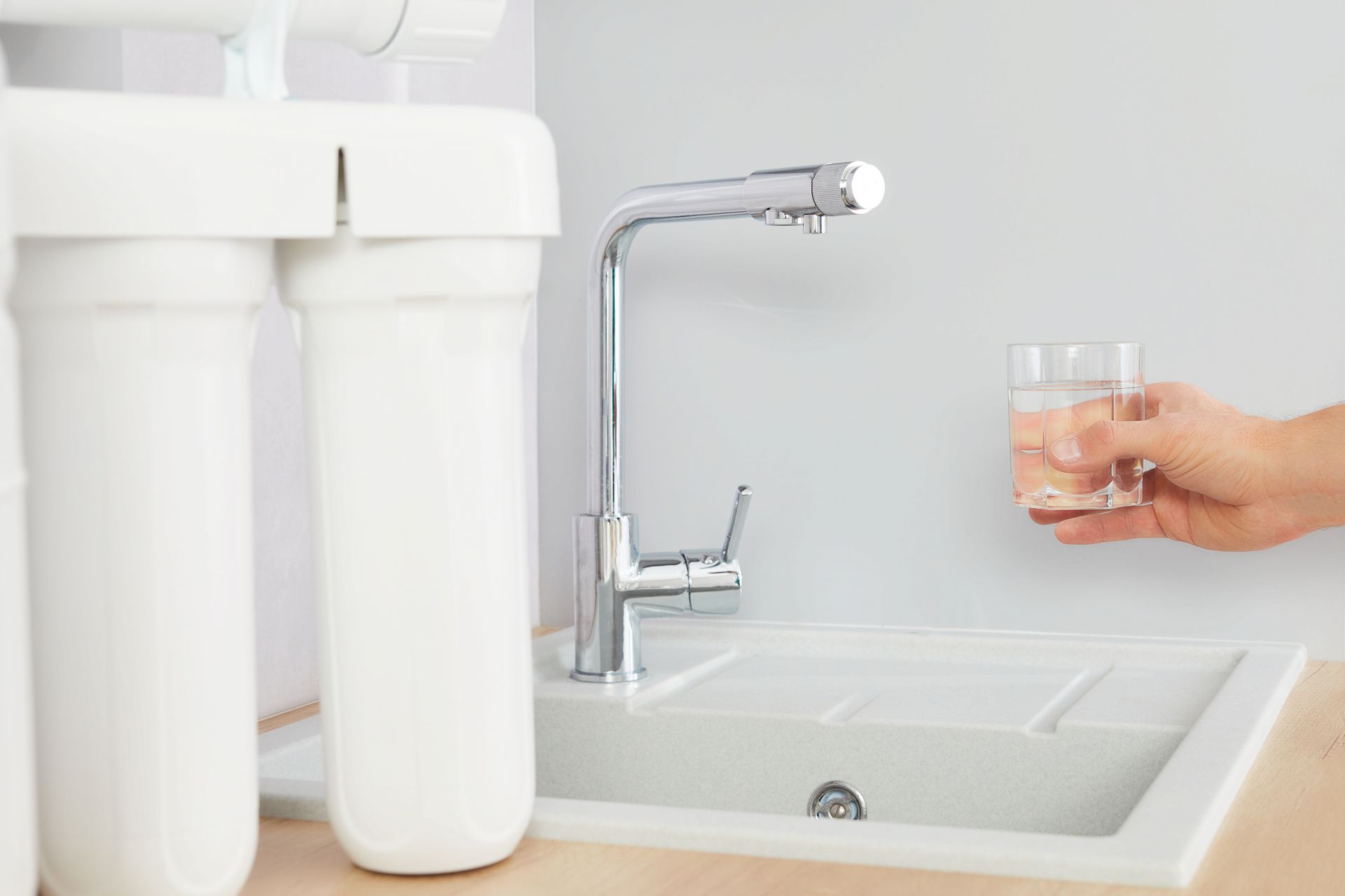 A person is pouring water from a faucet into a glass.