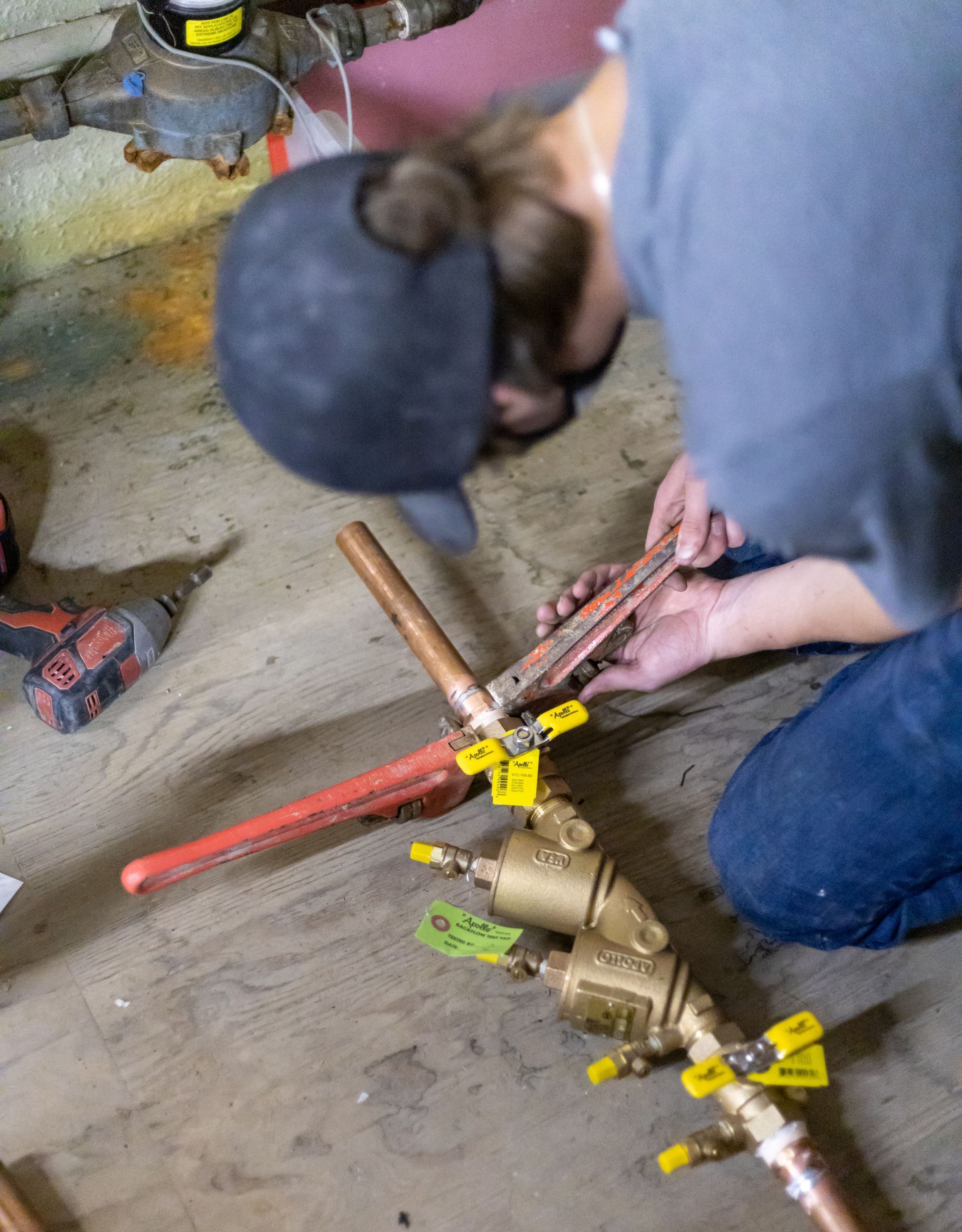 A plumber is measuring a sink drain with a tape measure.