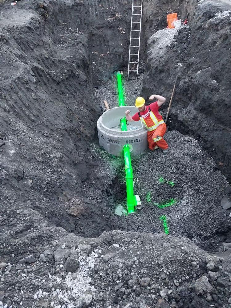 A green hose is coming out of a manhole cover.