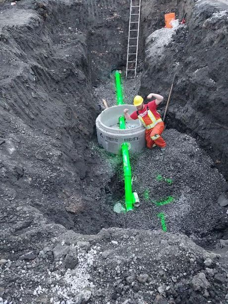 A green hose is coming out of a manhole cover.