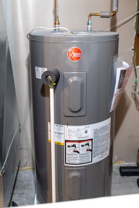 A man is fixing a water heater in a bathroom.