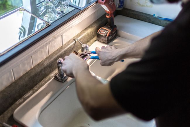 A plumber is fixing a sink in a bathroom.