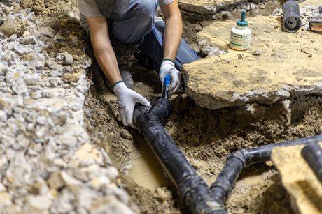 A plumber is working on a pipe with a wrench.