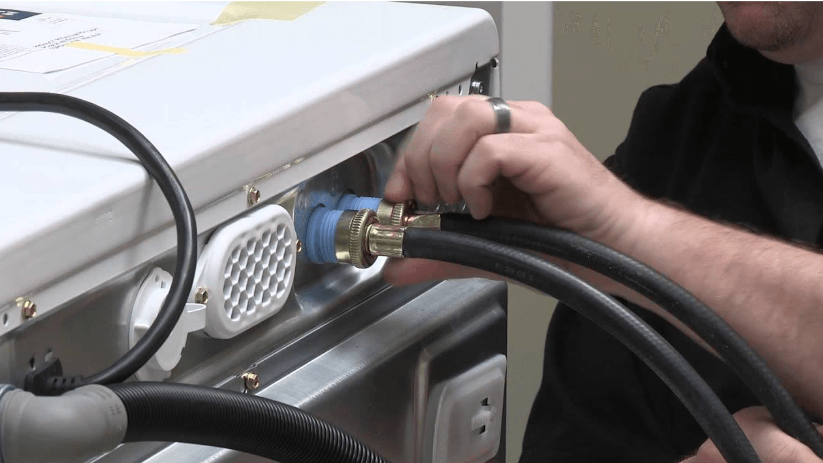 A man is plugging a hose into a washing machine.