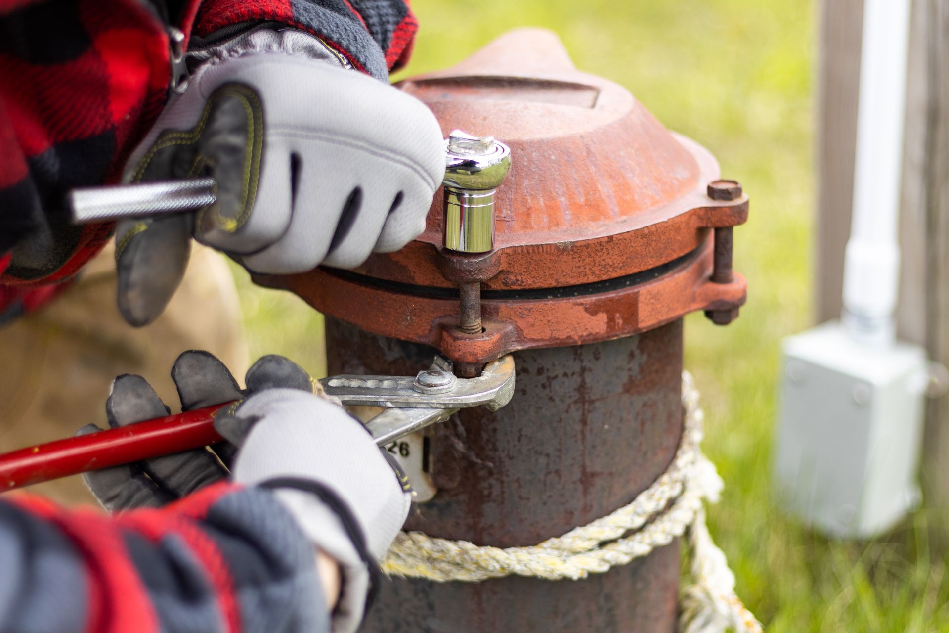 A man is fixing a fire hydrant with a wrench.