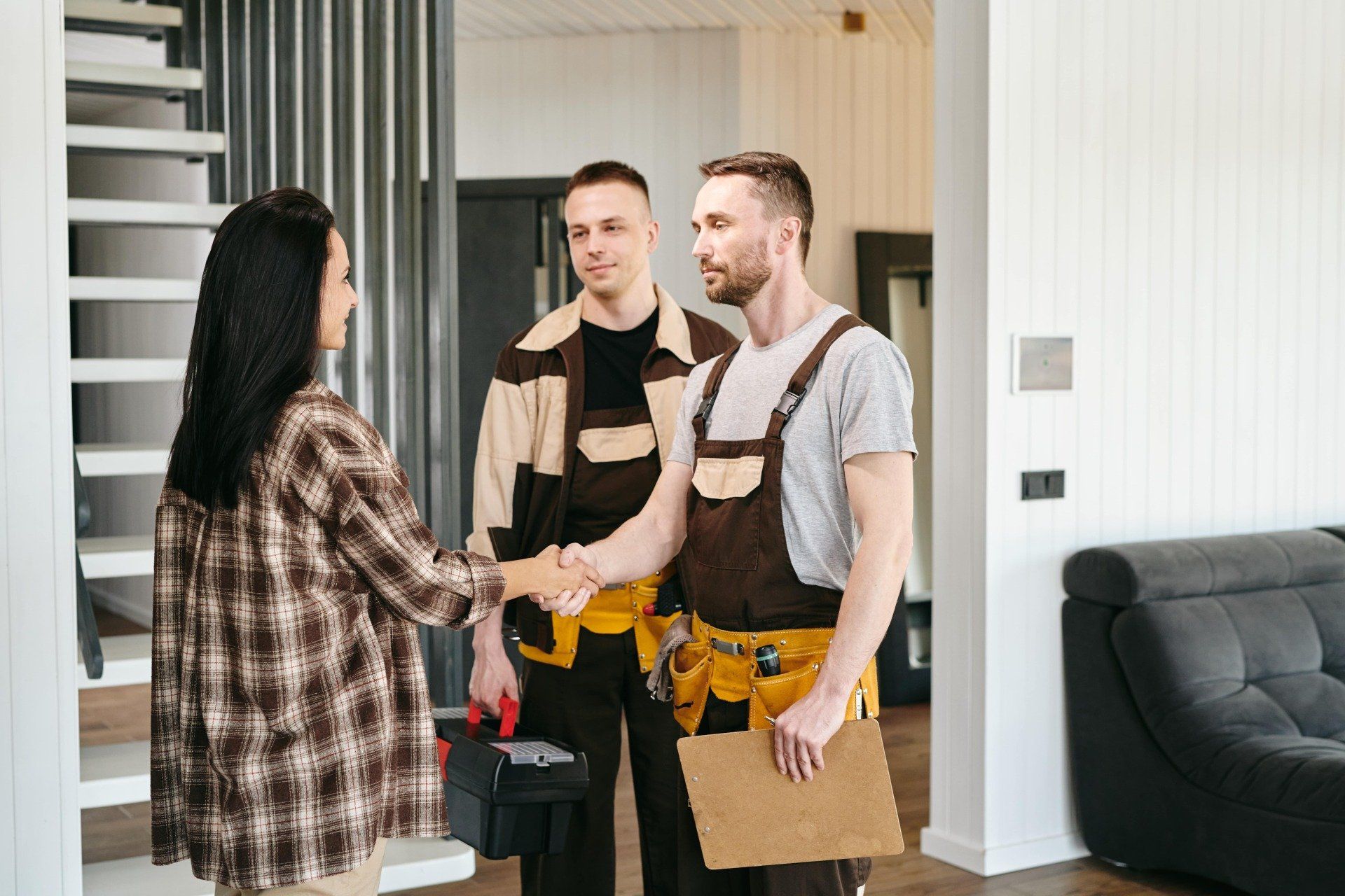 A woman is shaking hands with a construction worker in a living room.