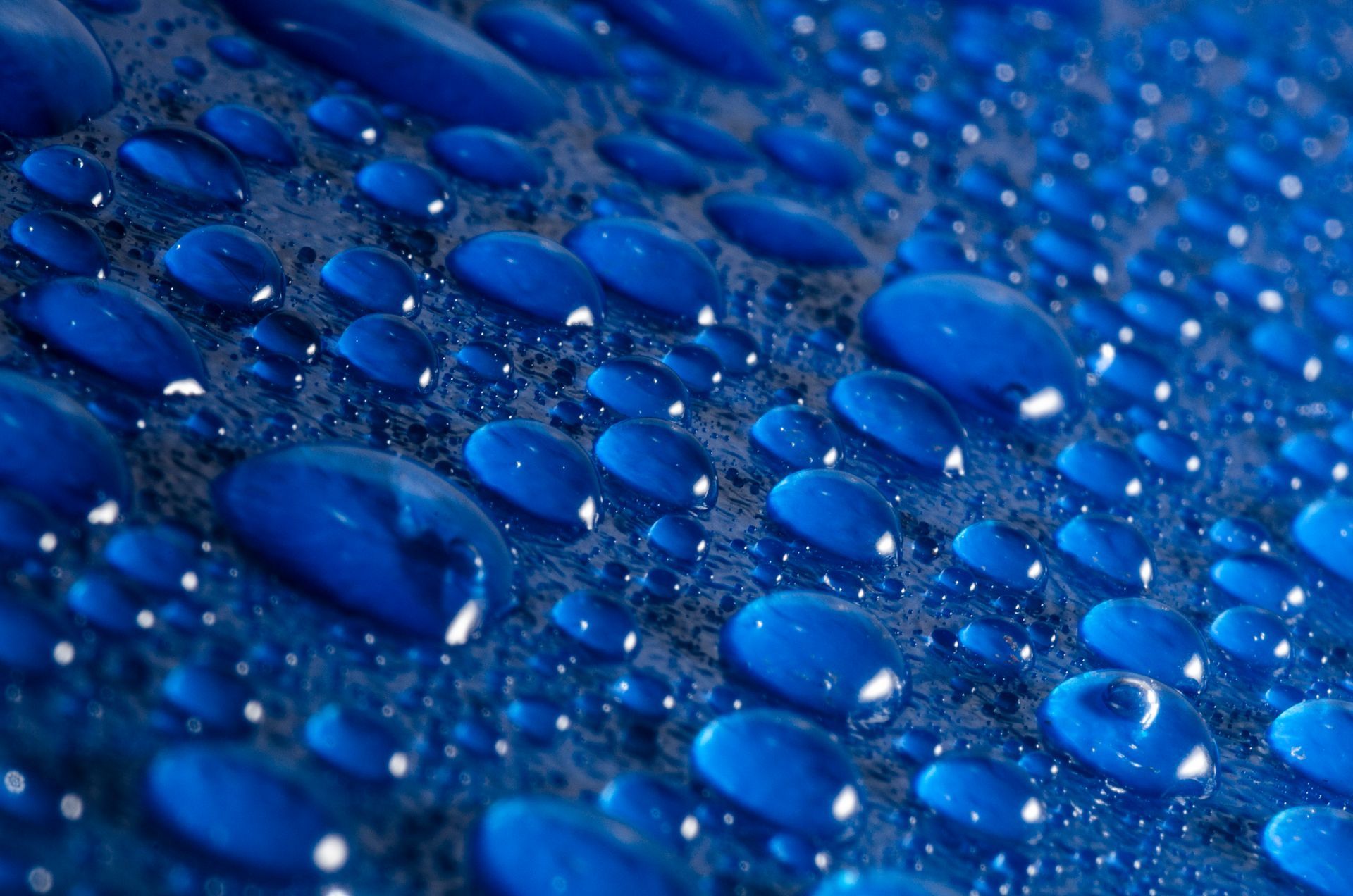 A close up of water drops on a blue surface.