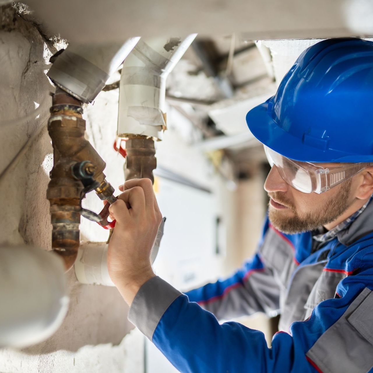 A person is working on a blue pipe with a wrench.