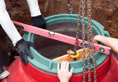 A person is using a level to check the level of a manhole cover.