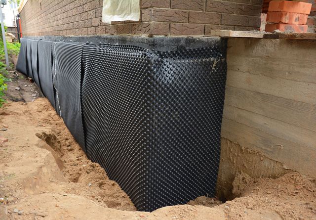 A drainage system is being installed on the side of a house.