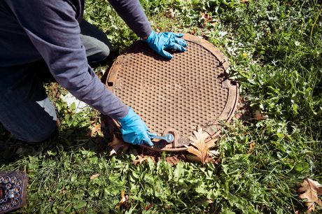 A green septic tank with a ladder attached to it is in the middle of a grassy field.