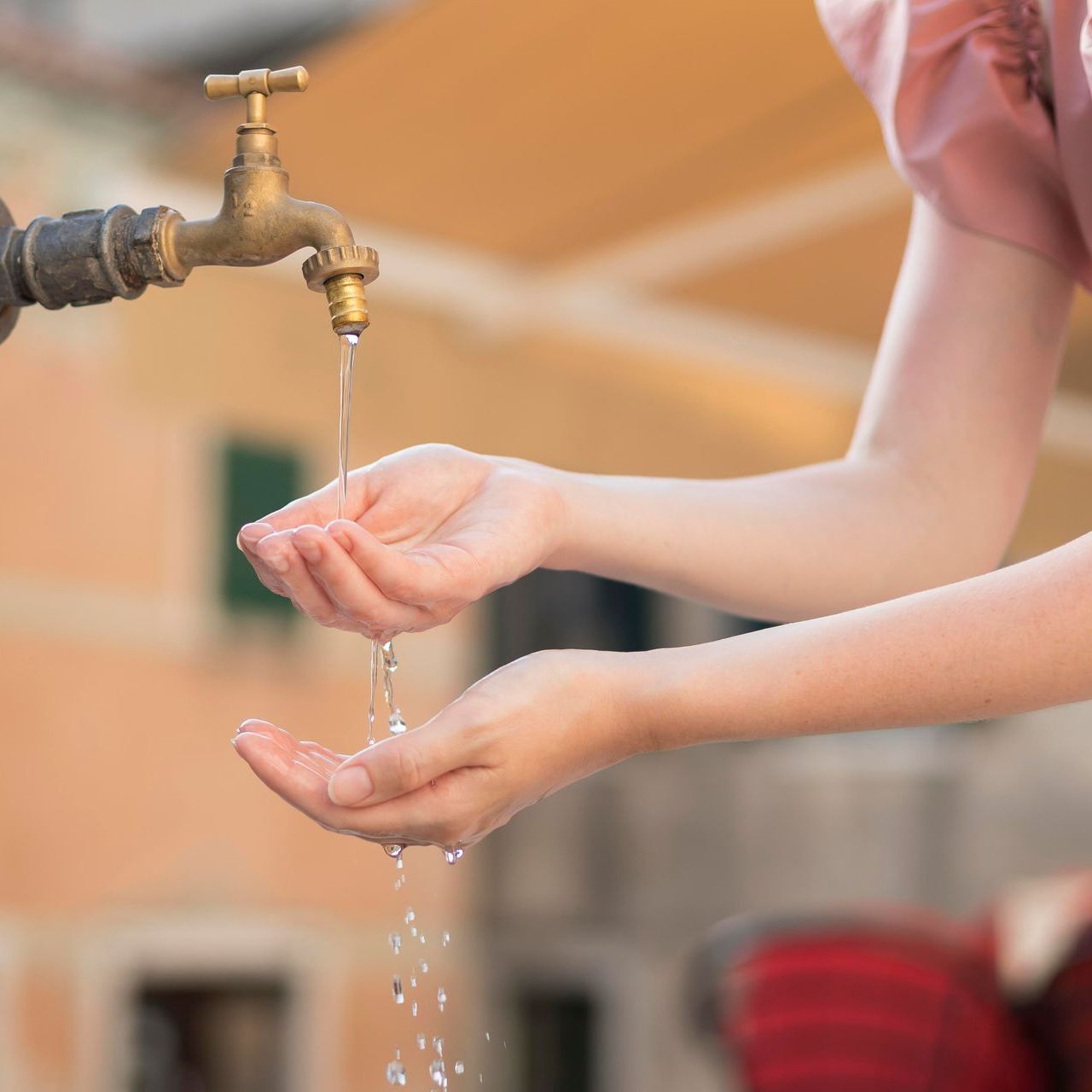 A woman is washing her hands under a faucet