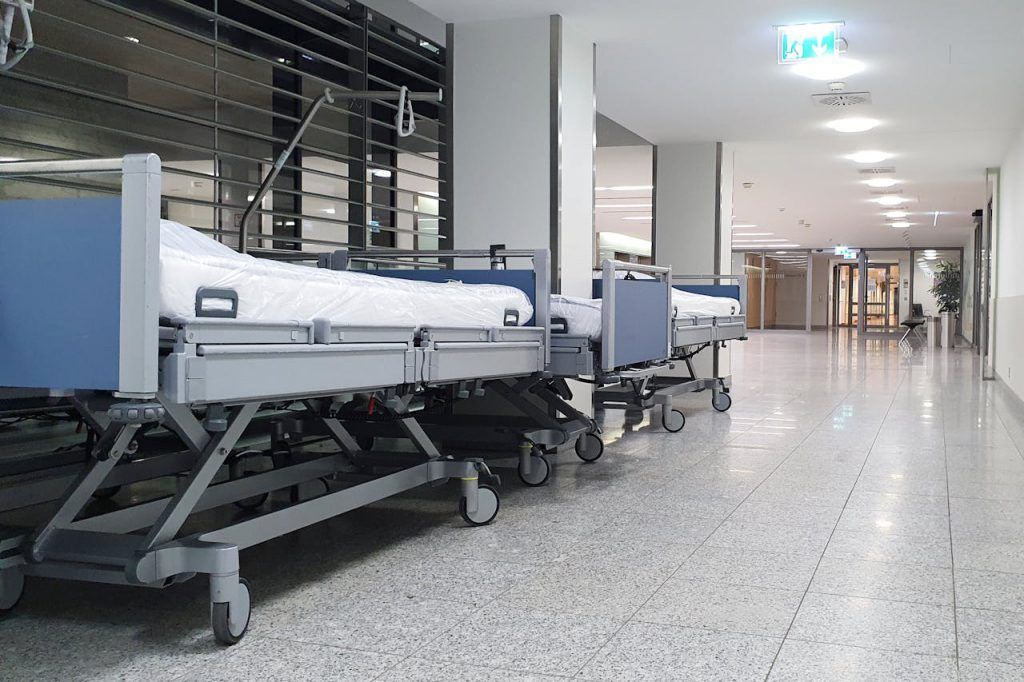 A row of hospital beds are lined up in a hospital hallway.
