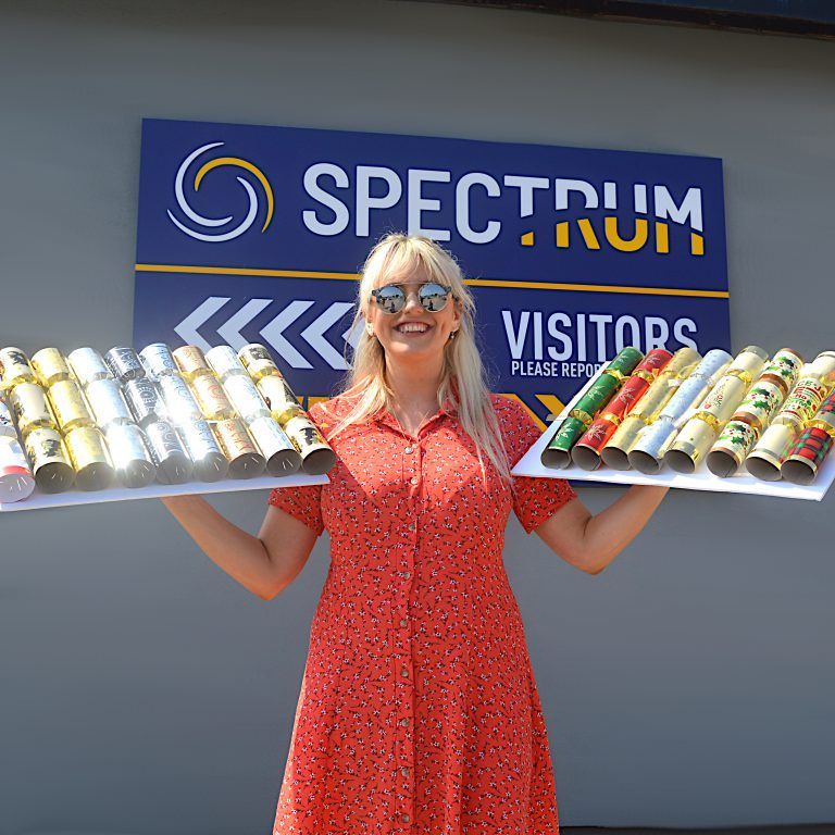 A woman in a red dress is holding two trays of crackers in front of a spectrum sign.