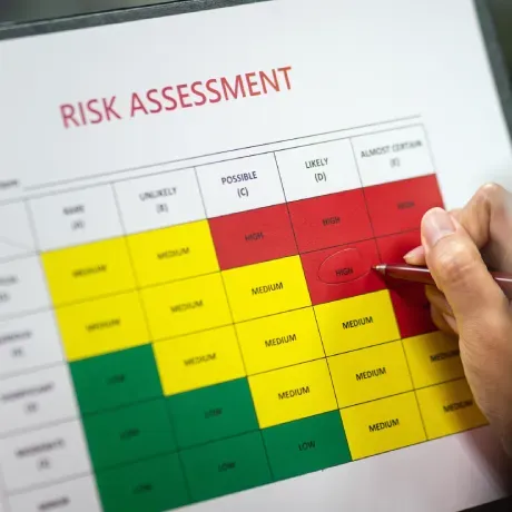 A person is holding a pen over a risk assessment chart