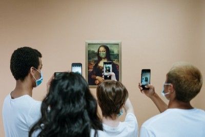 A group of people are taking pictures of a painting with their phones.