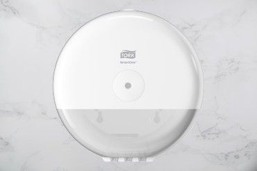 A white toilet paper dispenser is sitting on top of a white marble counter.
