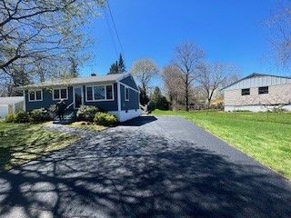Blue house with a black driveway under a clear, blue sky.