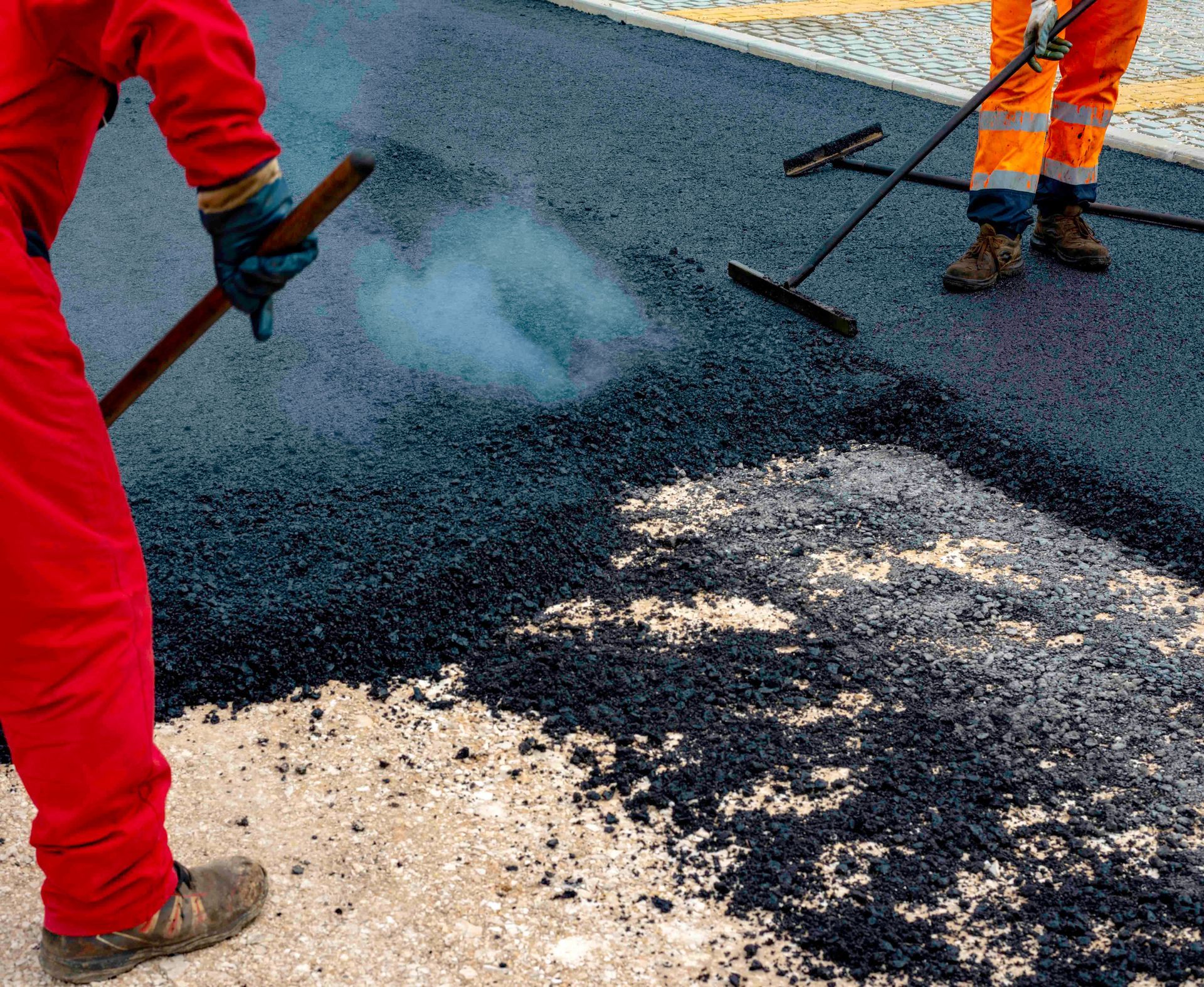 Paving crew spreading fresh asphalt for a new driveway