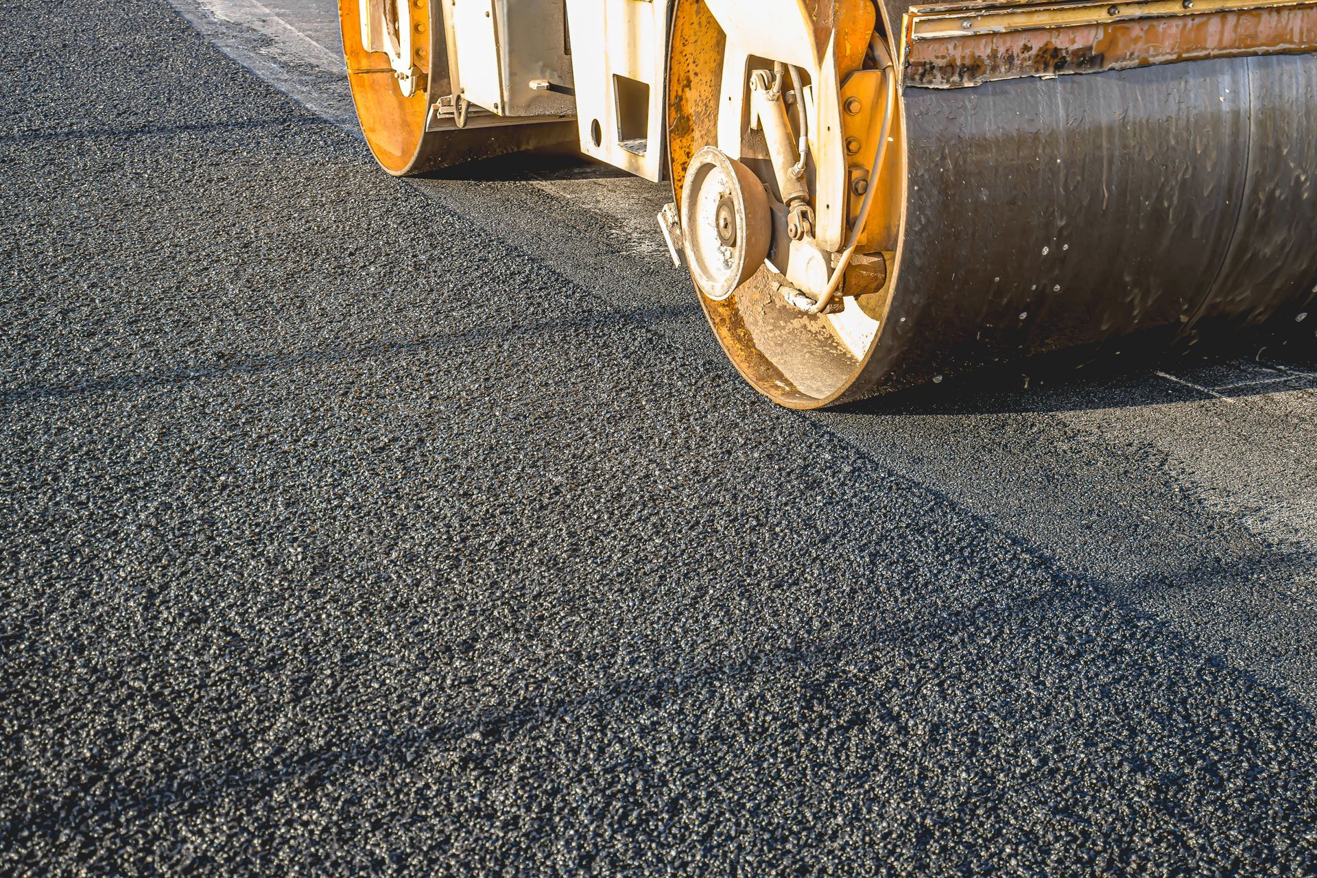 asphalt paving contractor operating a roller to compact freshly poured asphalt asphalt paving contractor operating a roller to compact freshly poured asphalt