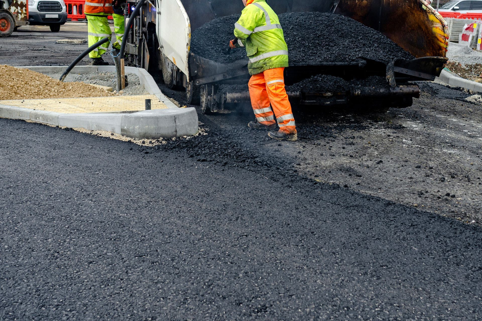 Commercial asphalt paving contractor on site applying hot asphalt to the road.