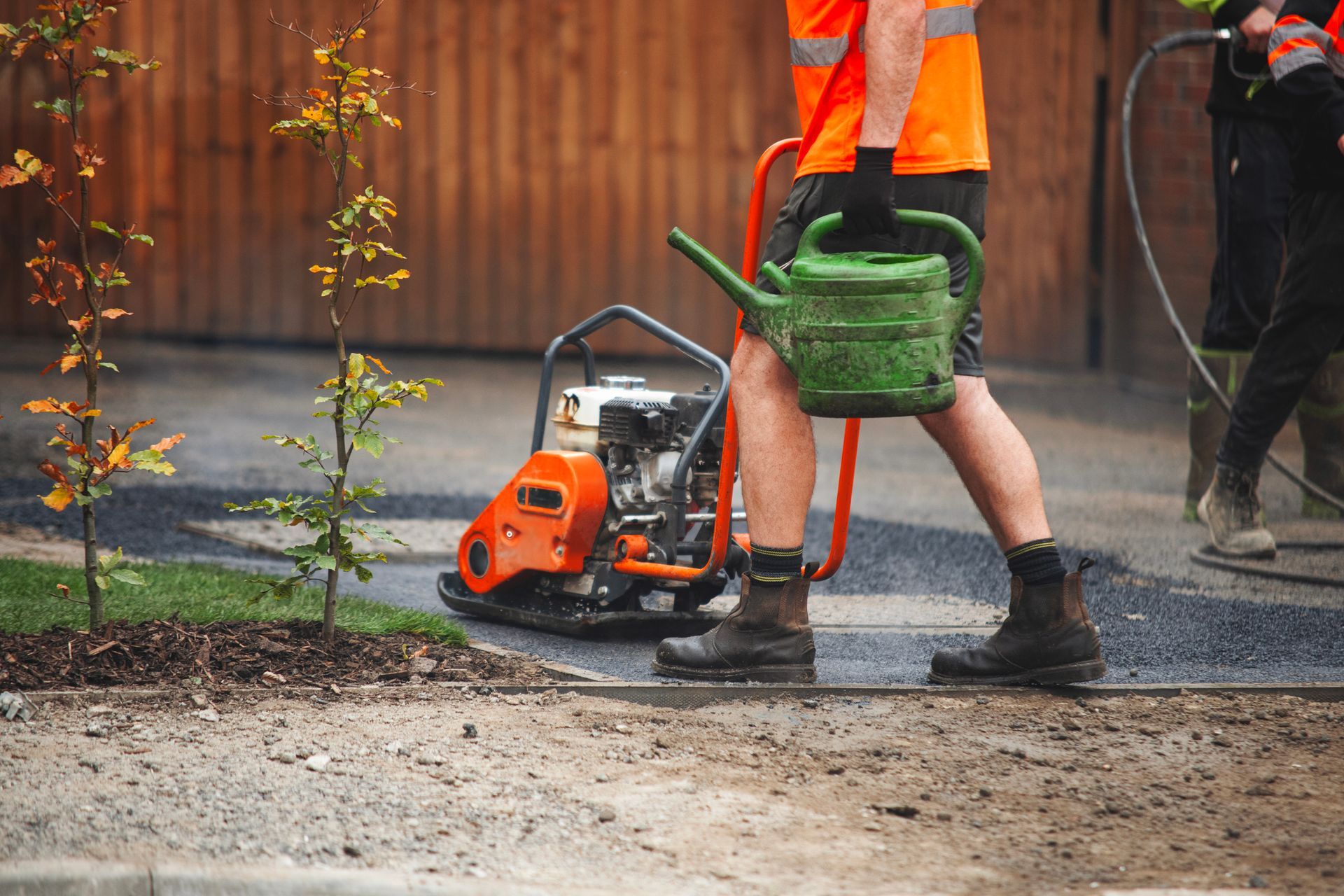 Two workers work on a road repair project, laying hot asphalt in a residential area. Two workers work on a road repair project, laying hot asphalt in a residential area.