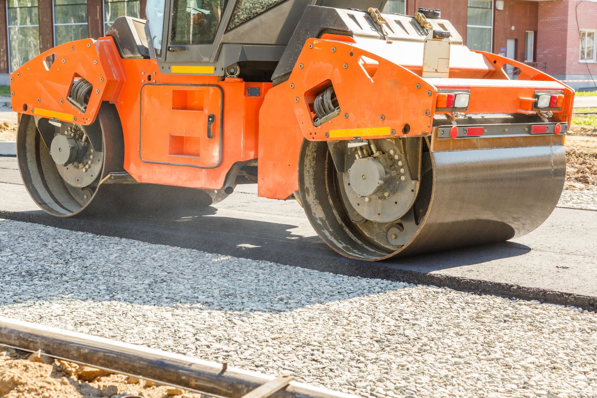 A road roller is rolling asphalt on a road.