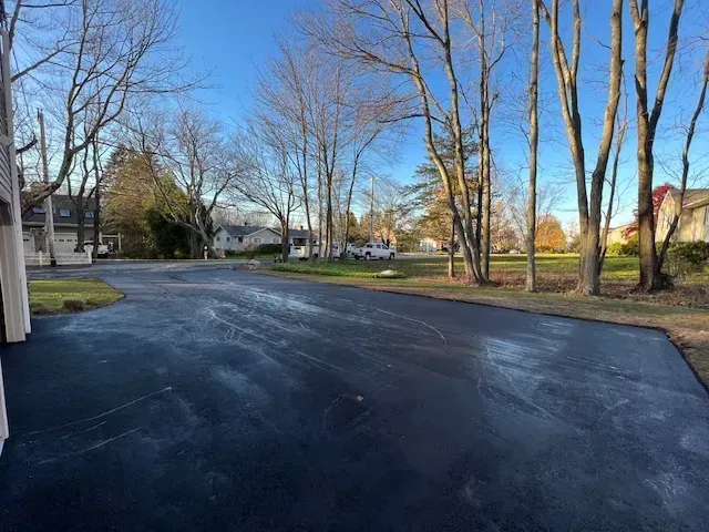 Black Asphalt Driveway Surrounded By Trees In Residential - Worcester, MA - Patriot Seal Coating & Paving