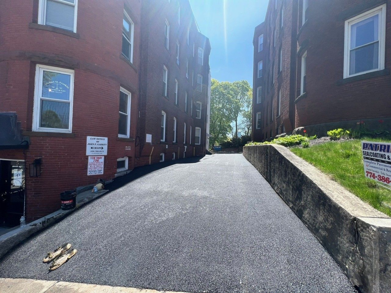 Asphalt driveway between brick buildings, sunny day.