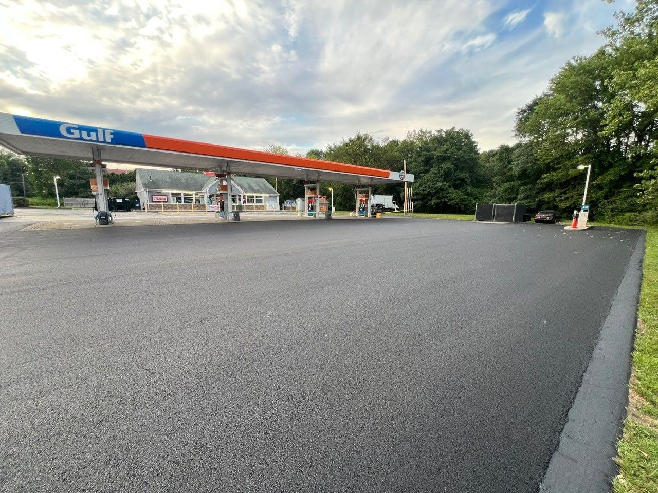 Newly paved gas station forecourt with Gulf canopy; cloudy sky.