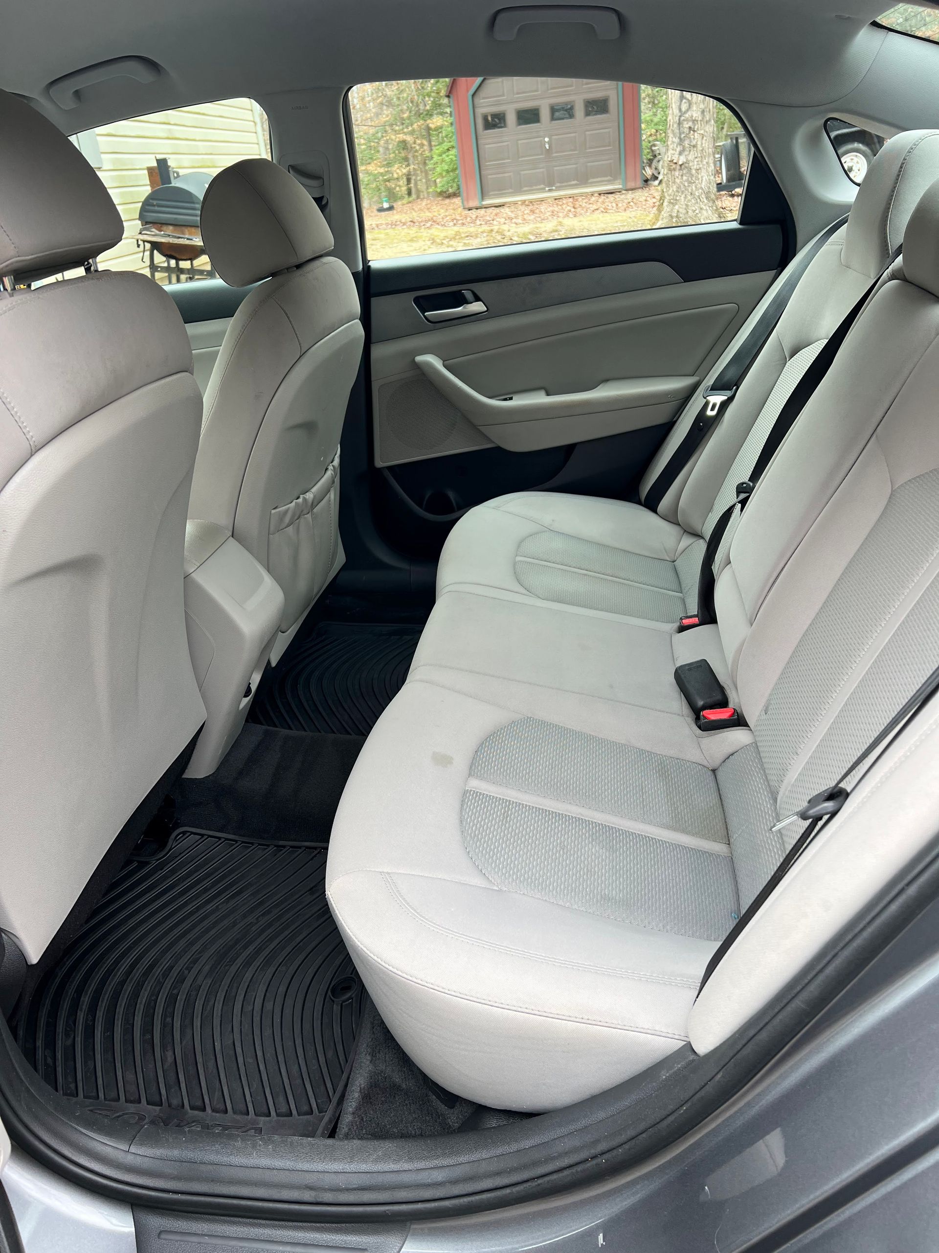 the back seat of a car with white seats and a black mat .