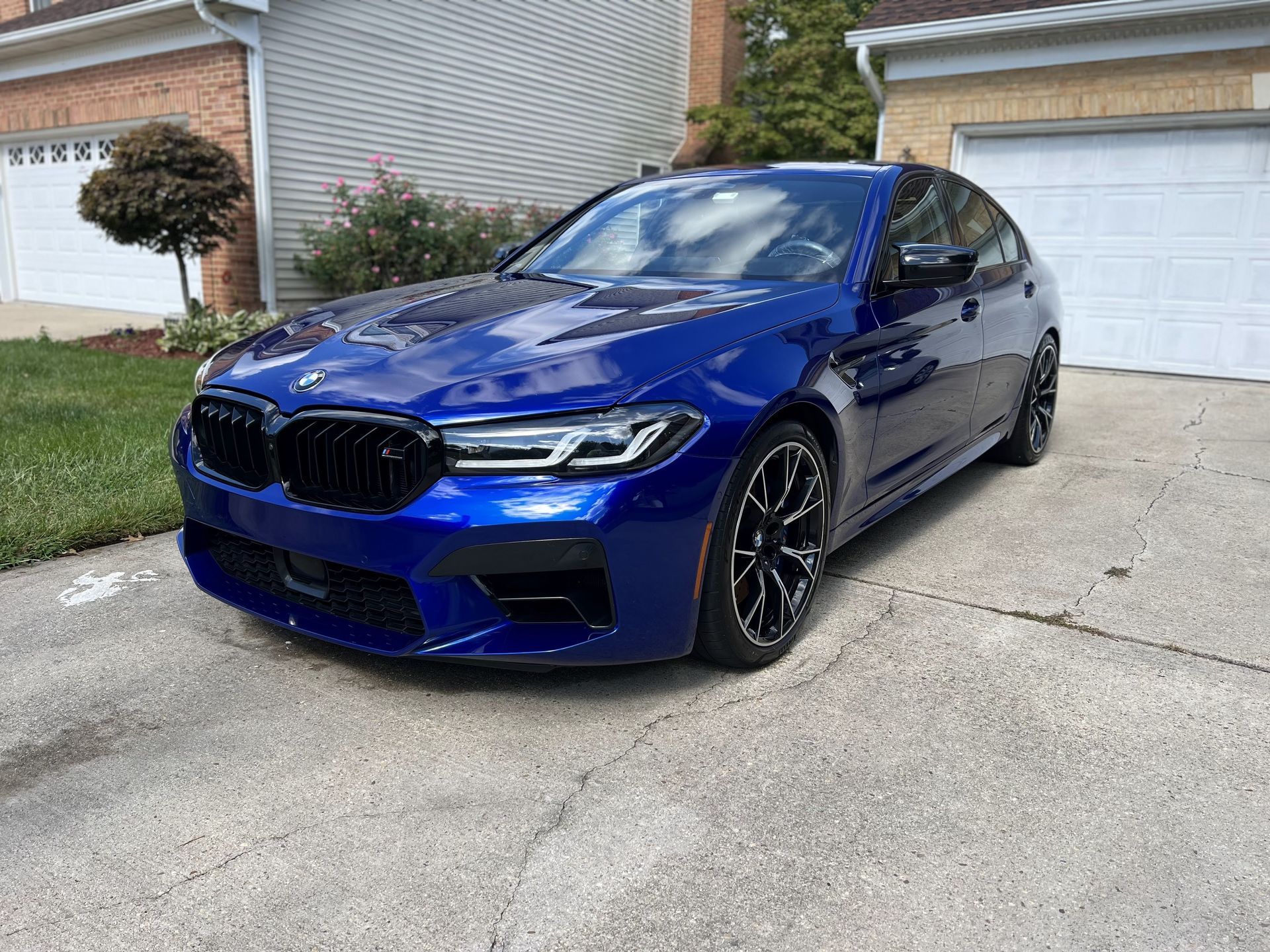 a blue bmw m5 is parked in a driveway in front of a garage .
