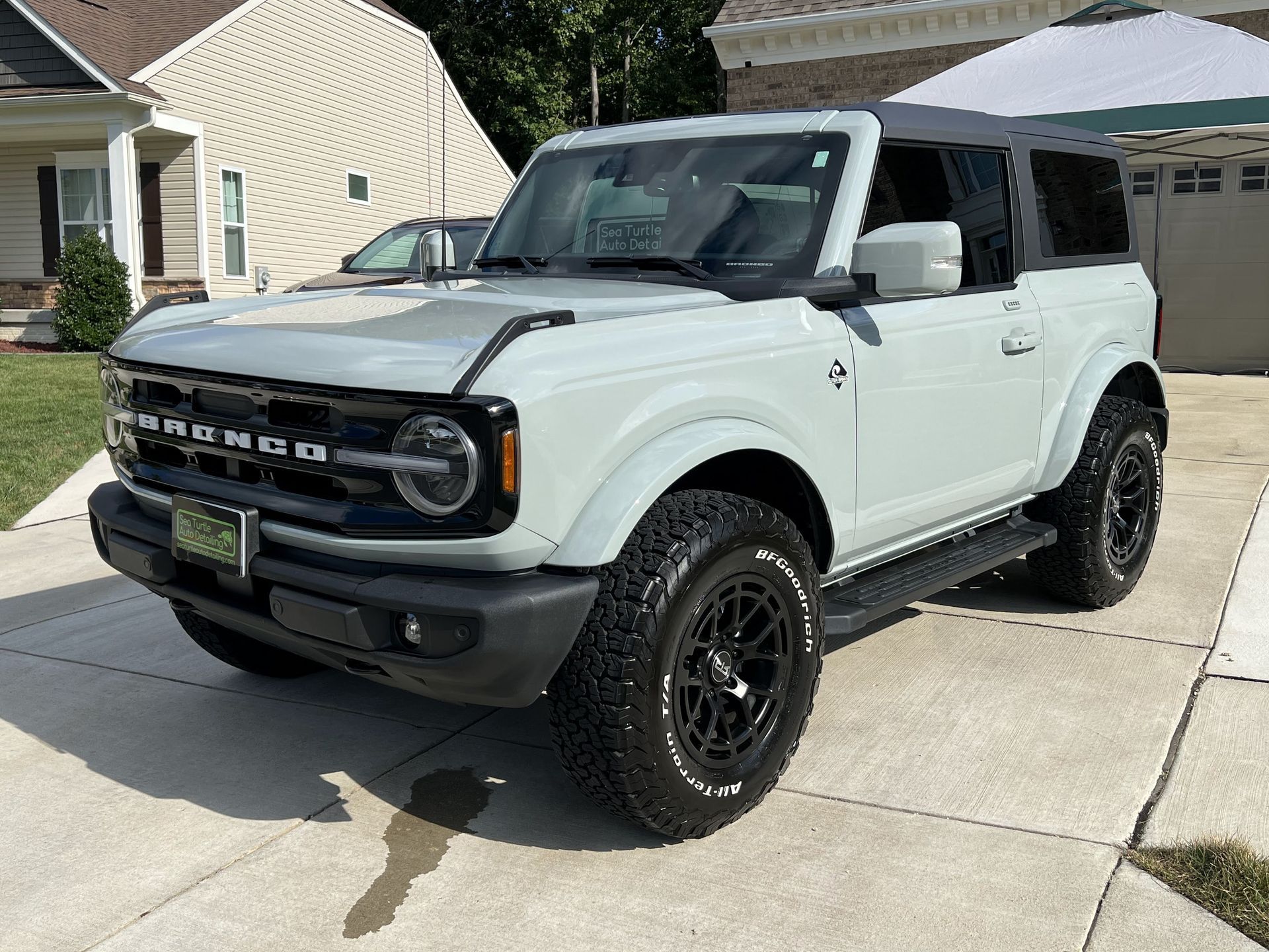 a white ford bronco is parked in a driveway in front of a house .